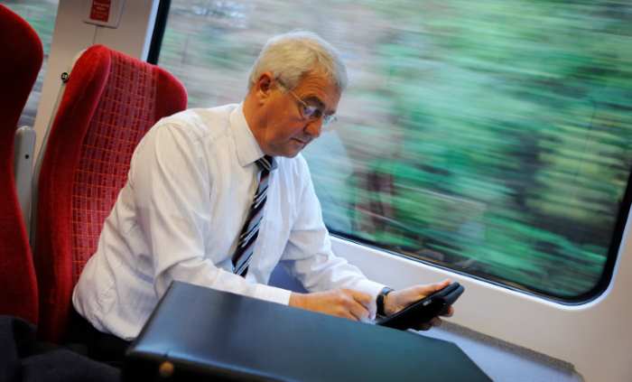 man working on the train and checking his mobile phone