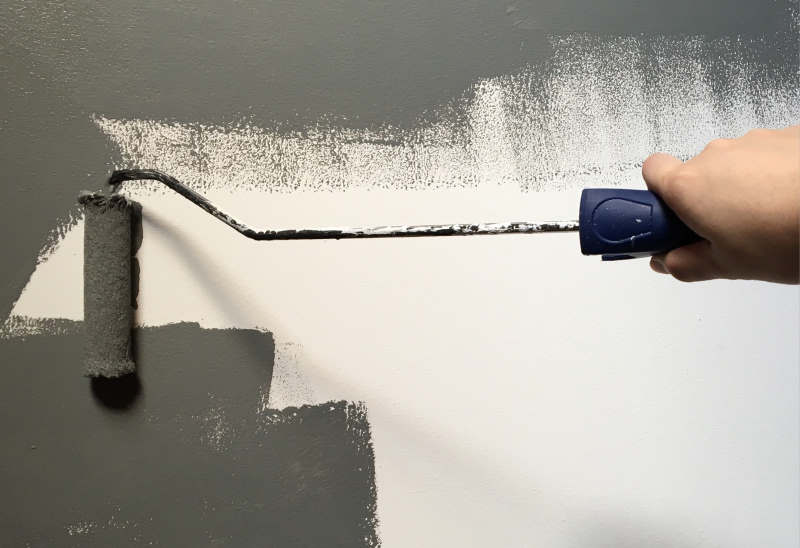 person-holding-paint-roller-while-painting-the-wall