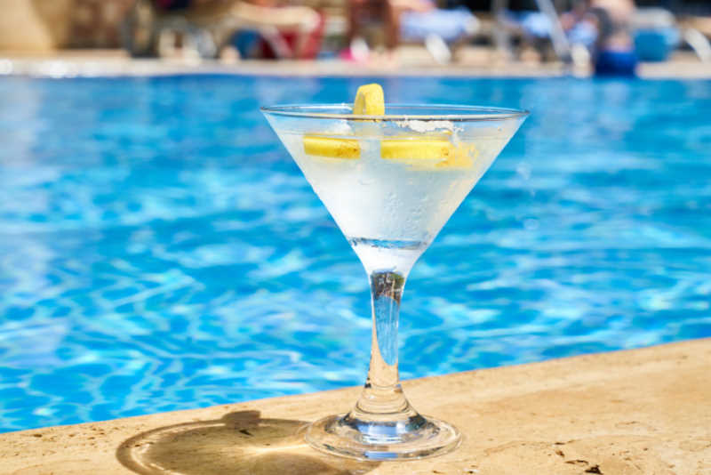 glass of white alcohol cocktail near swimming pool
