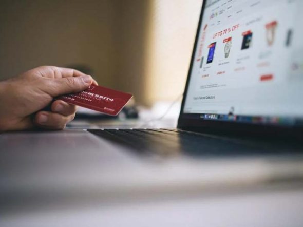 customer holding a credit card near a laptop screen