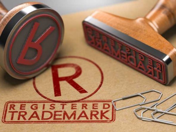 3D illustration of two rubber stamps with the text registered trademark and the symbol R over brown paper background. Trade-mark Registration Concept