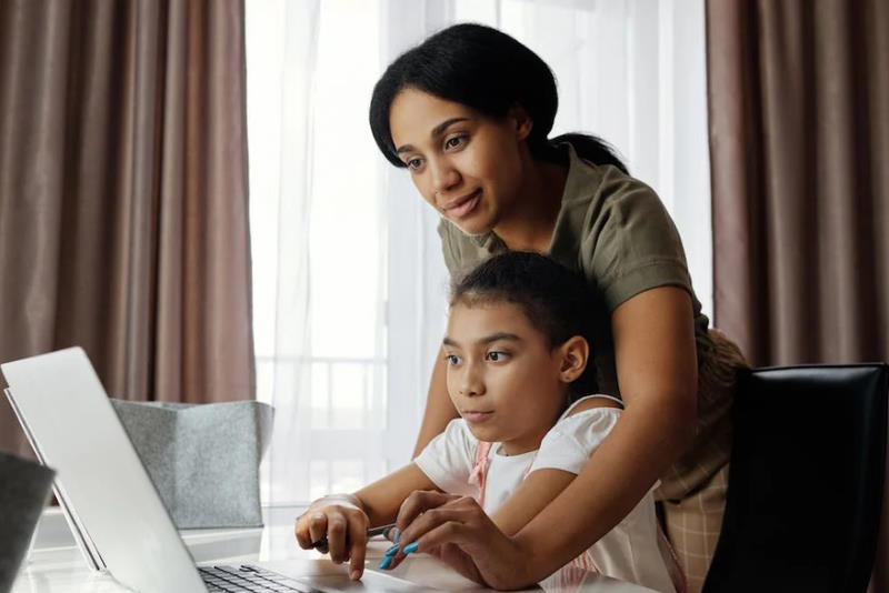 mother helping her daughter study online