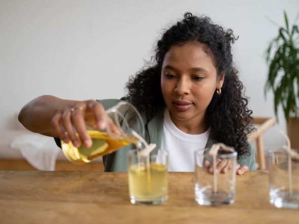 Woman Pouring Yellow Liquid in Clear Glass