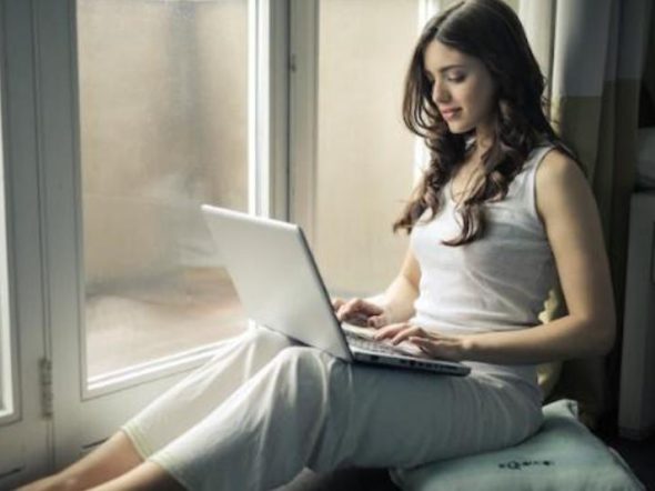 woman working on her laptop sitting near a window