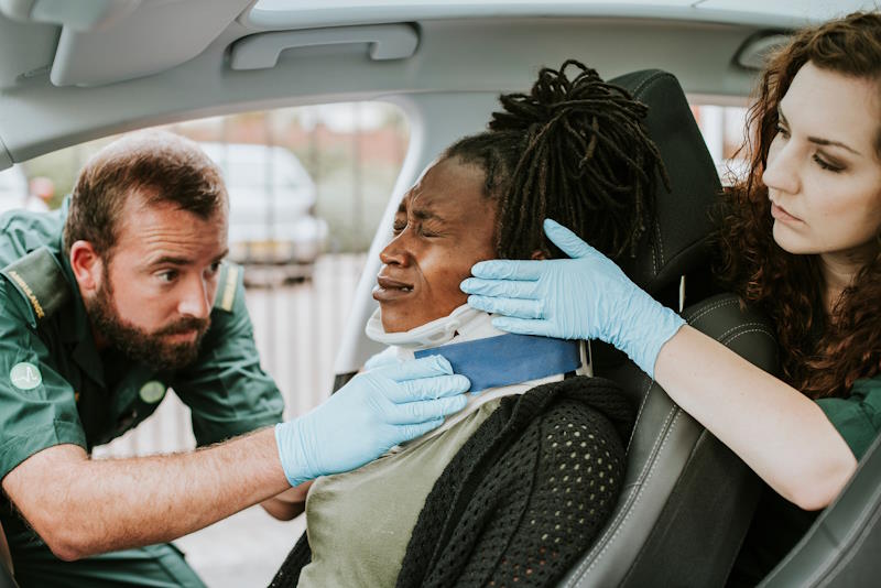 Paramedic placing a cervical collar to an injured woman from car