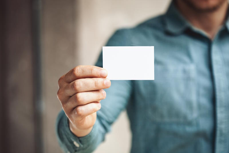 Man holding business card on blurred background