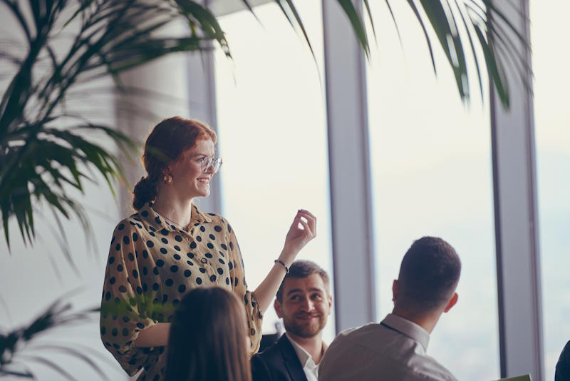 A group of young business professionals in a modern office attentively listens to colleague presentation, showcasing a dynamic and collaborative atmosphere as they exchange ideas and strive for success