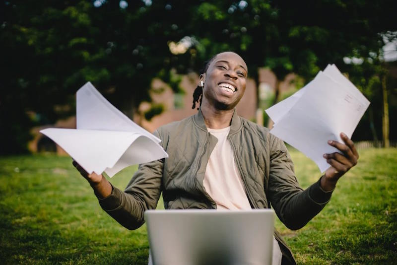 happy employees with papers on hand working on his laptop