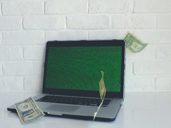 laptop with banknotes floating in the air