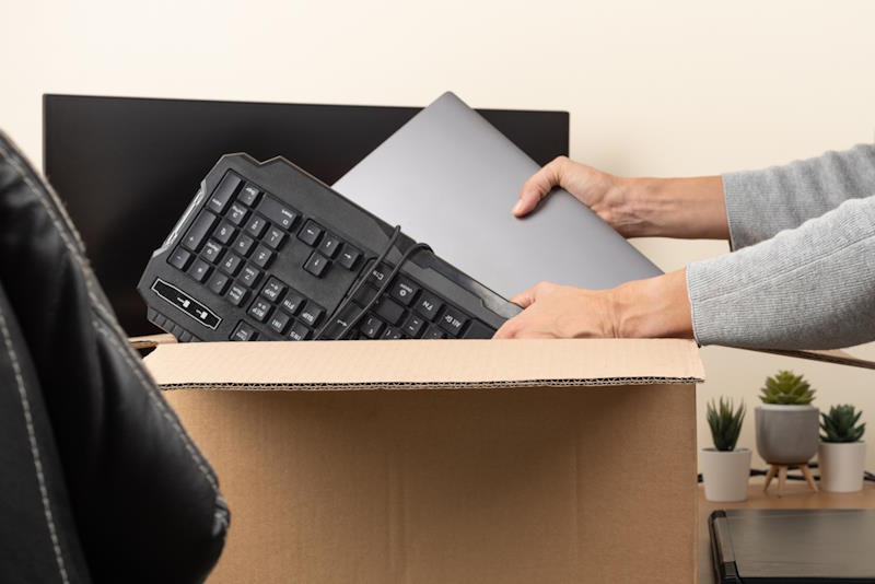 Woman hands put old laptop and keyboard in box with old used computers and gadget devices for recycling. Planned obsolescence, e-waste, donation, electronic waste for reuse, refurbish, recycle concept.